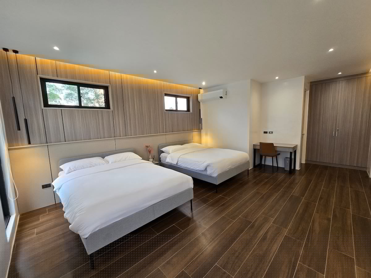 Spacious bedroom with two queen beds and wood panel accent wall